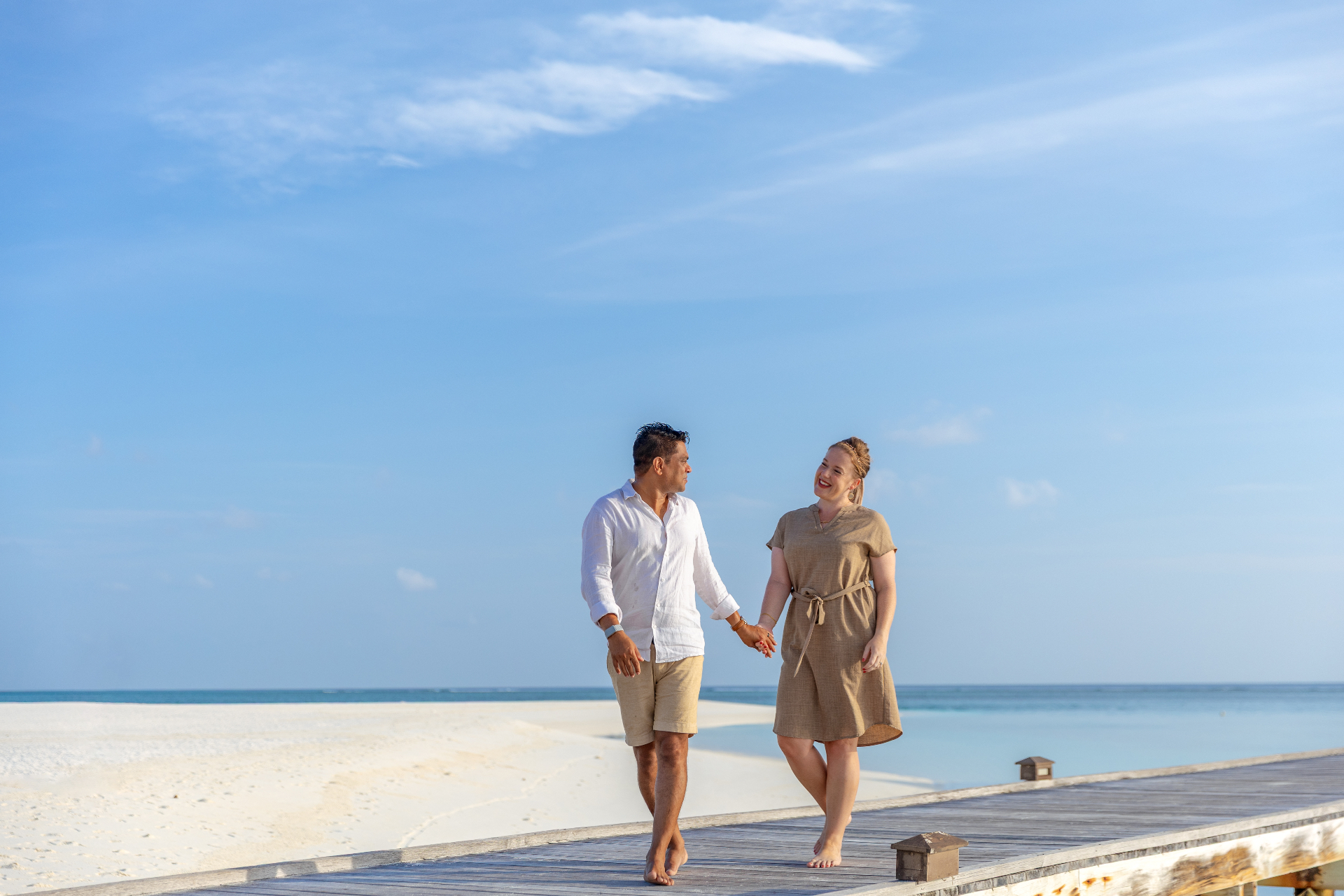Nadine and Sobah walking hand in hand along a Maldives boardwalk