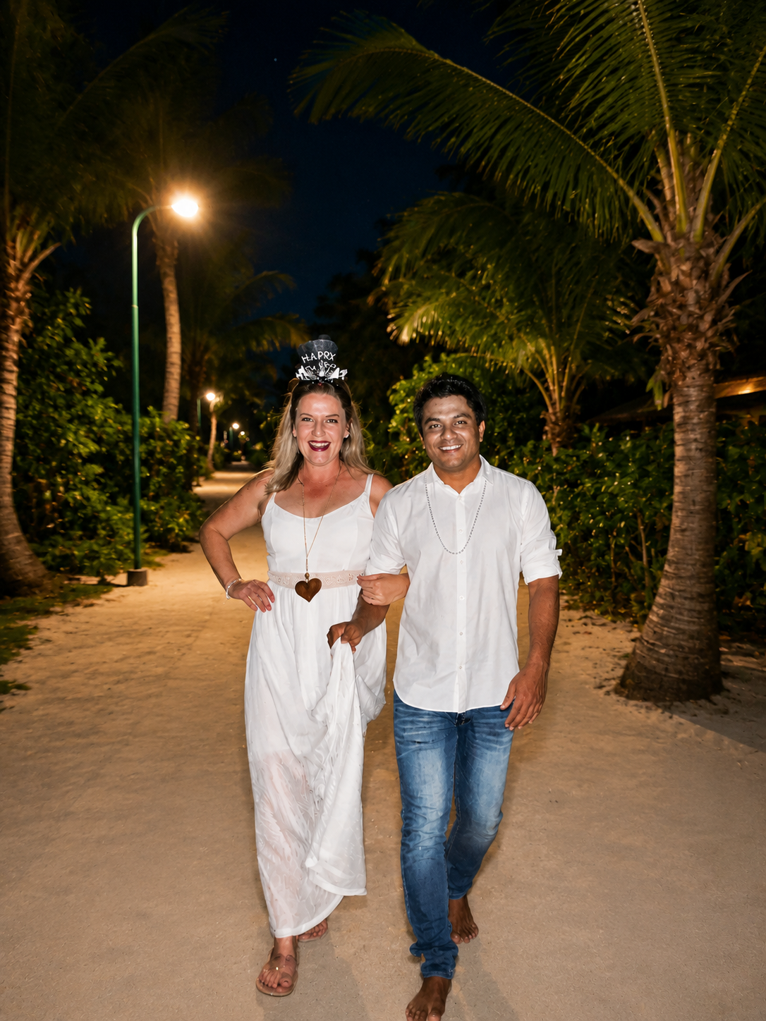 Nadine and Sobah walking a palm-lined path at night